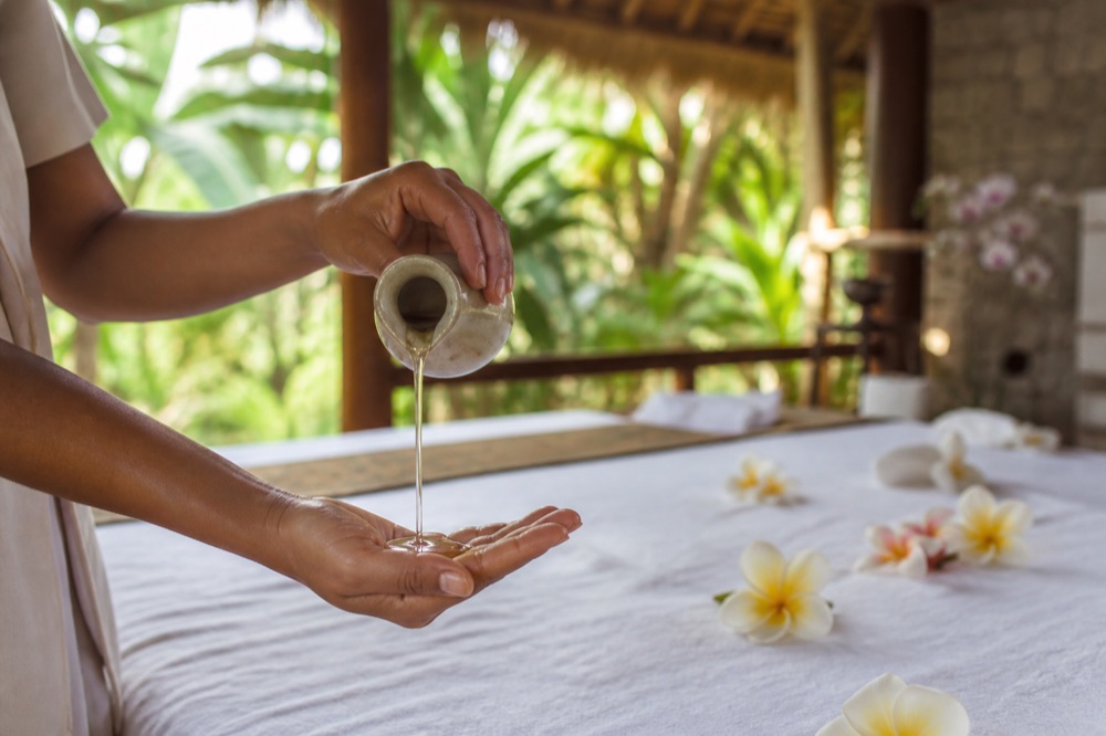 Body massage: massage oil poured into a cupped hand above a linen-covered table (7 of 7)